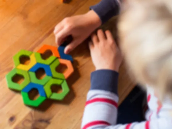 A child fitting hexagon pieces into a wooden puzzle